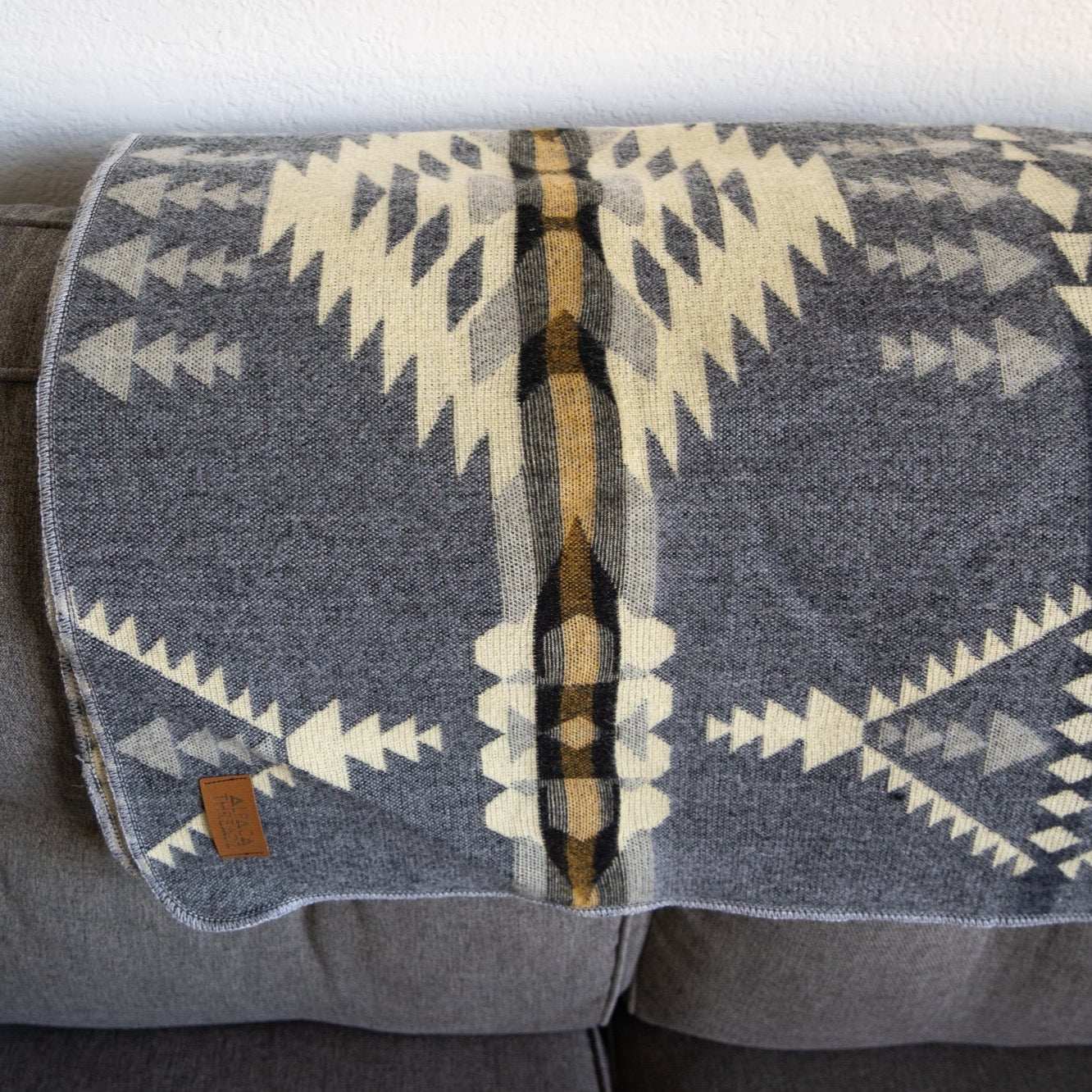 Andean Alpaca Wool Blanket - Cloud with vibrant reversible patterns on a sofa.