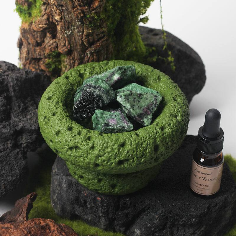 Green Moon Diffuser - Forest Woods with essential oil bottle, set among natural stones and moss.