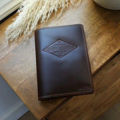 Handcrafted leather journal with embossing on cover, featuring waxed edges, on a wooden surface.