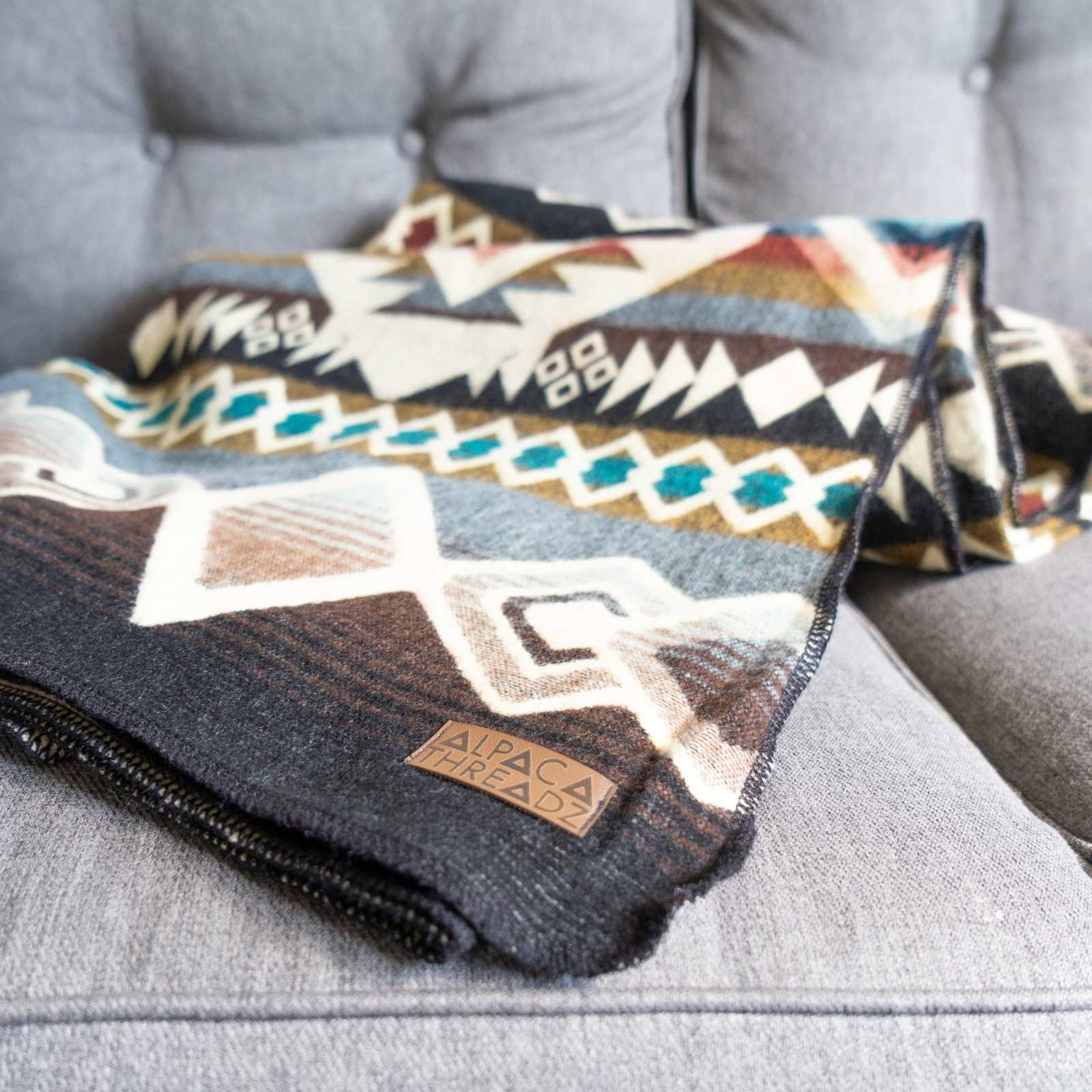 Andean Alpaca Wool Blanket – Inca with vibrant designs on a gray couch.