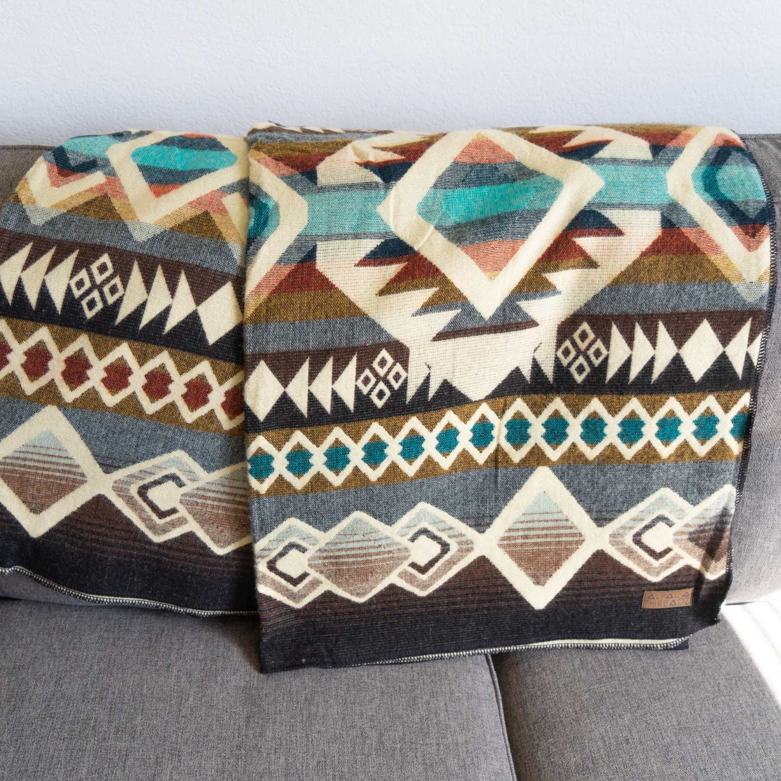 Andean Alpaca Wool Blanket - Inca with vibrant designs on a sofa.