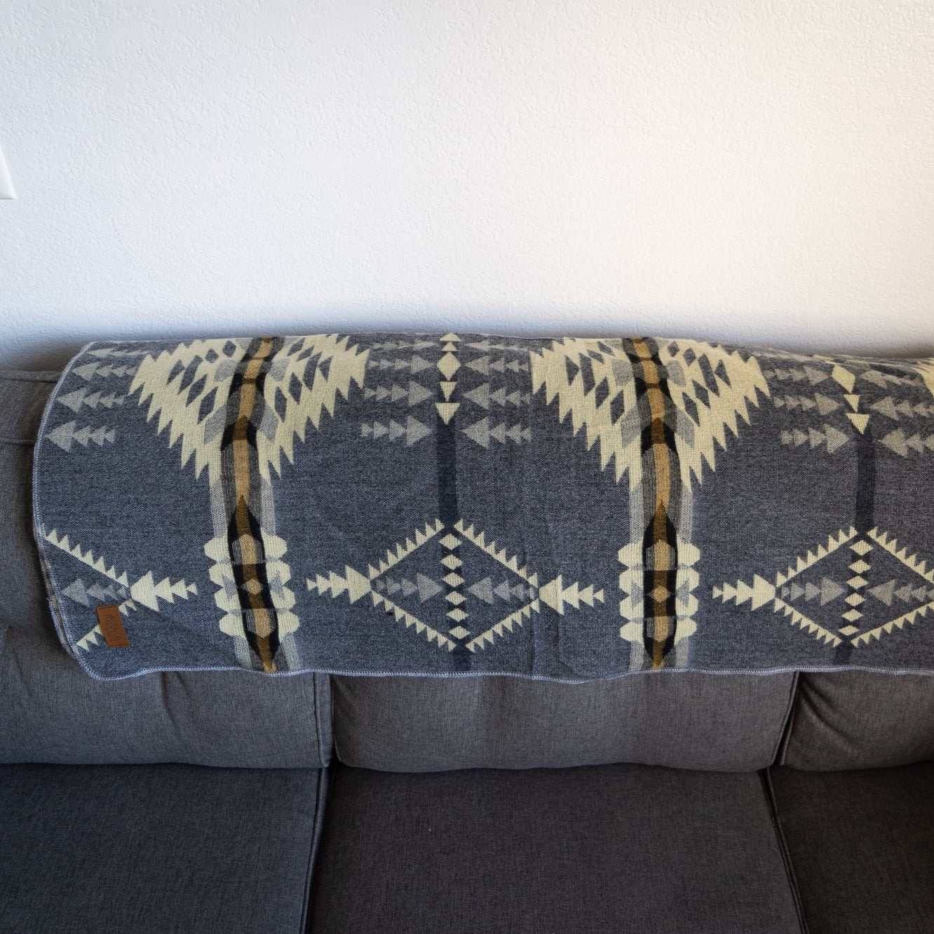 Andean Alpaca Wool Blanket - Cloud with vibrant pattern on a sofa, handmade by artisans in Ecuador.