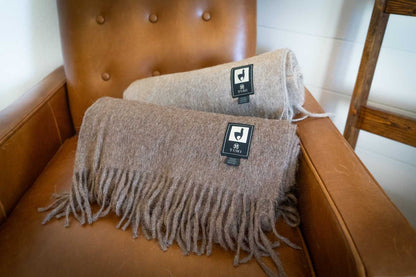 Alpaca Wool Throw Blankets with fringe on leather chair, available in solid colors.