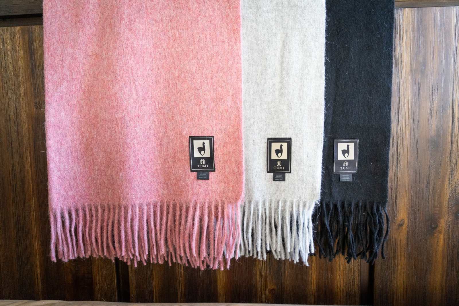 Alpaca Wool Throw Blanket with fringe in solid colors: pink, light gray, and black.