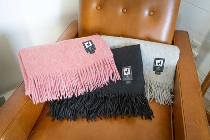 Alpaca Wool Throw Blanket in solid colors with fringe on a brown chair.