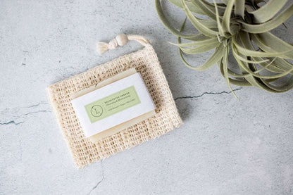 Eucalyptus soap on exfoliating soap saver with plant nearby, part of the Body Skincare Gift Box.