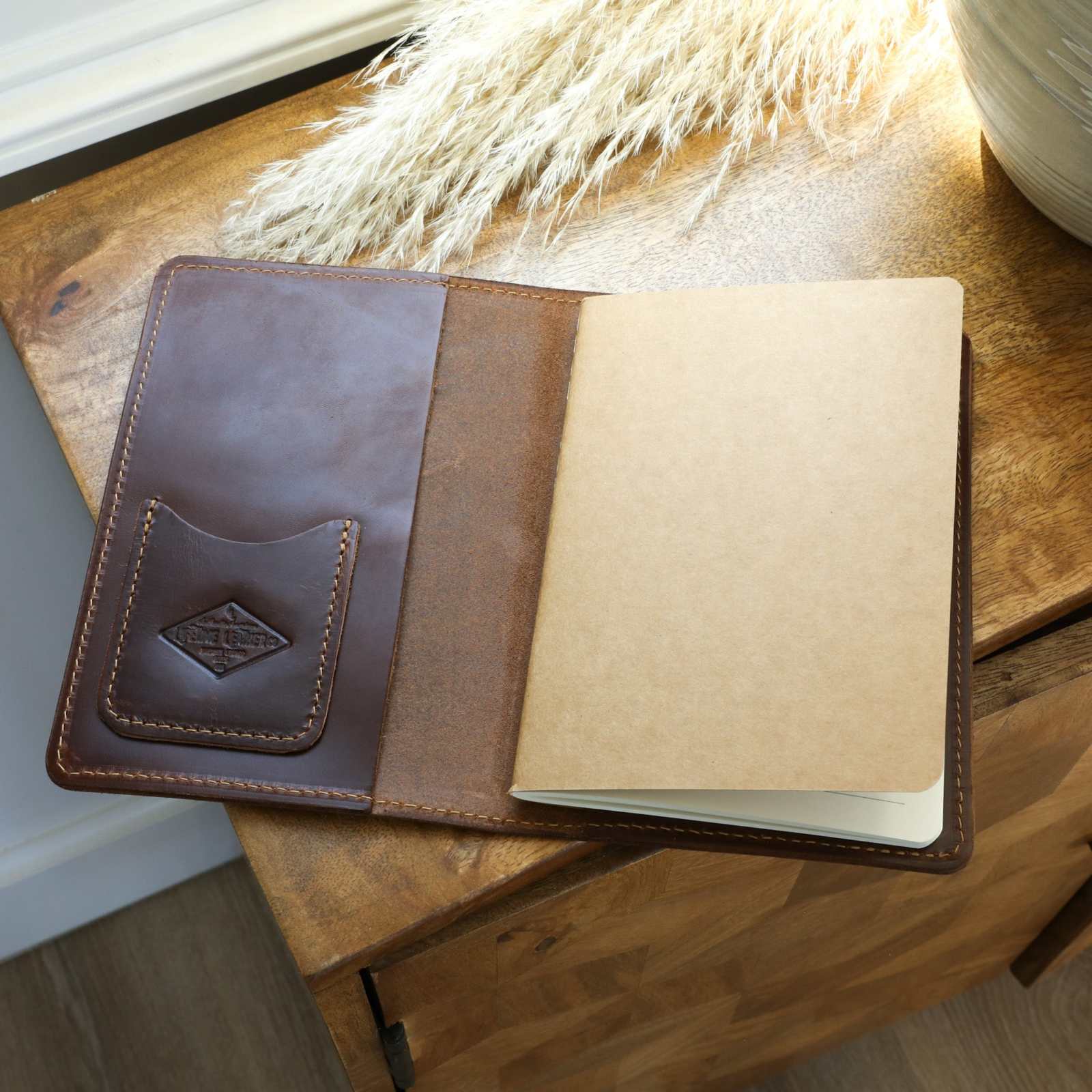 Handcrafted leather journal with card sleeve, featuring a free lined kraft paper insert on a wooden surface.