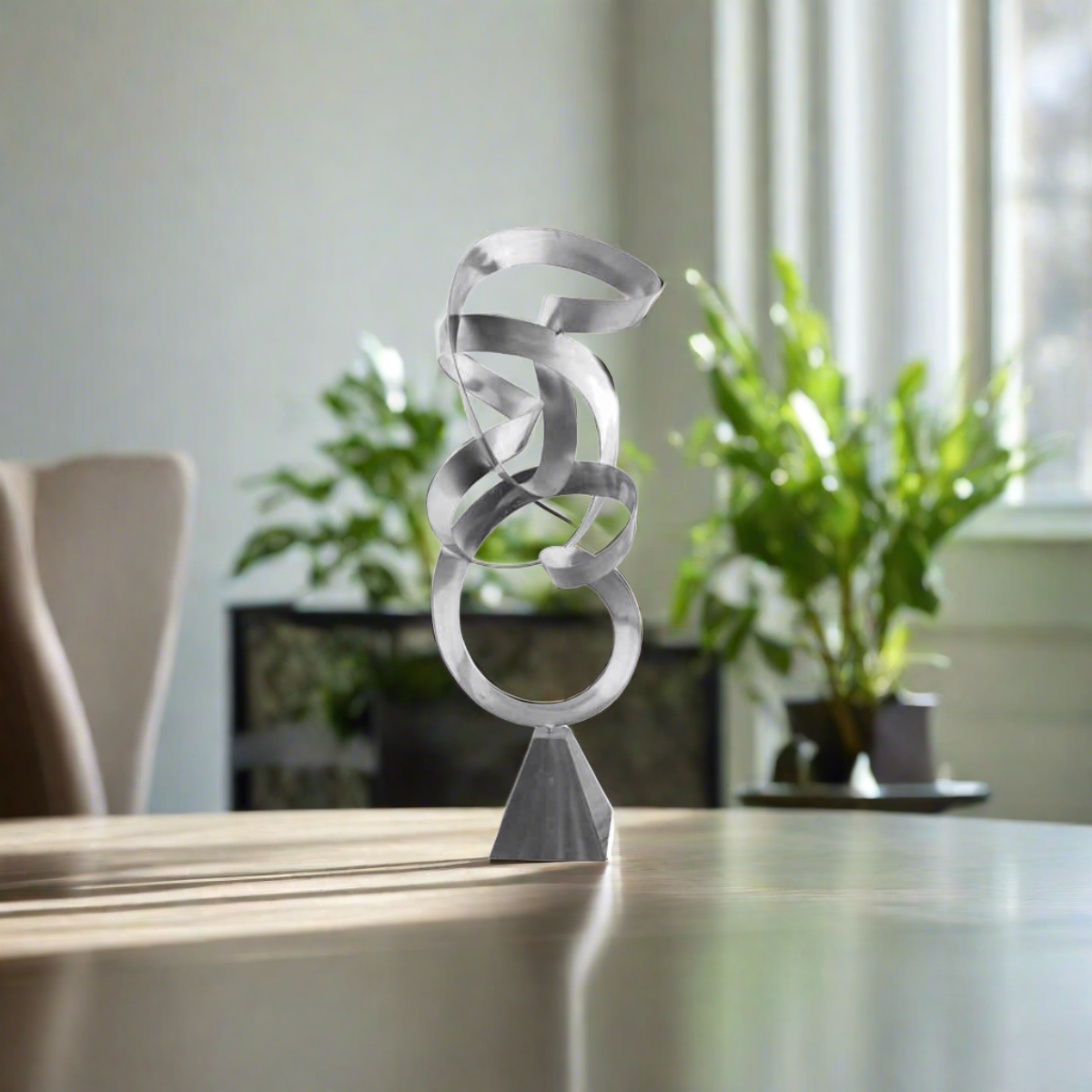 Infinite Path Metal Sculpture with stainless steel finish and swirling abstract design on a table in a modern interior.