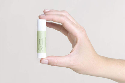 Hand holding eucalyptus lip balm from Body Skincare Gift Box.