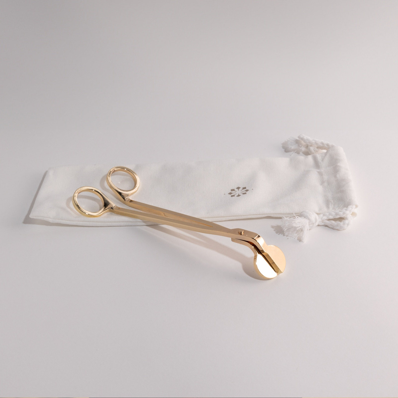 Candle snuffer and wick trimmer duo on white background with elegant pouch, essential for candle care.